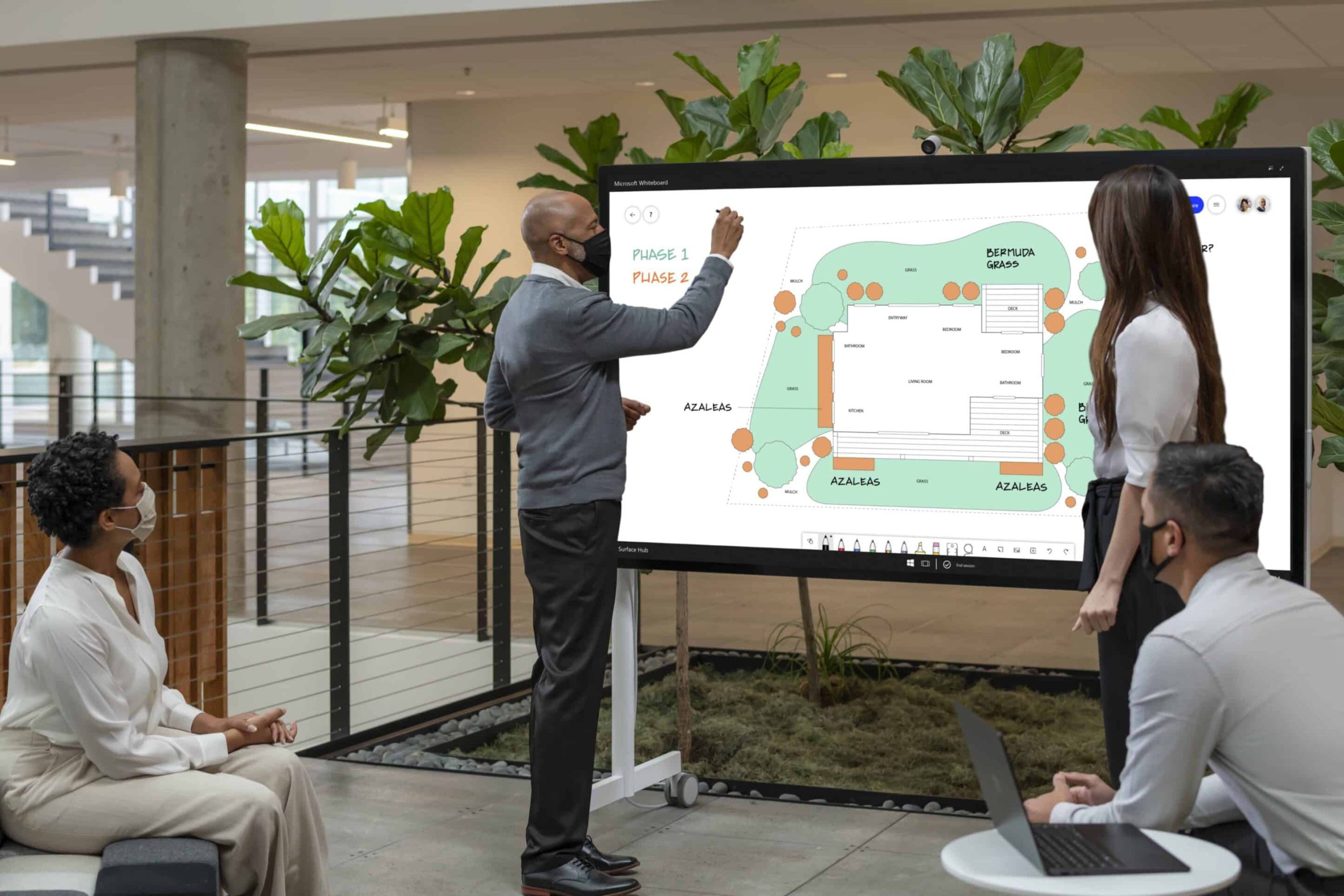 SUR21_Hub2S_Contextual_4747_RGB (1) two team members using Microsoft Surface Hub 2S in meeting with team